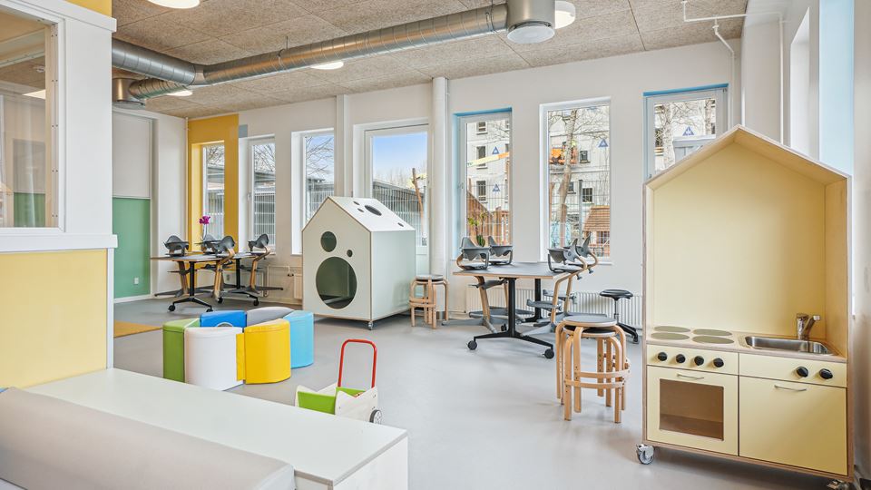 Lyst, farverigt grupperum i Børnehuset Edison, Hørkær 18, med legekøkken, legehus og store vinduer.