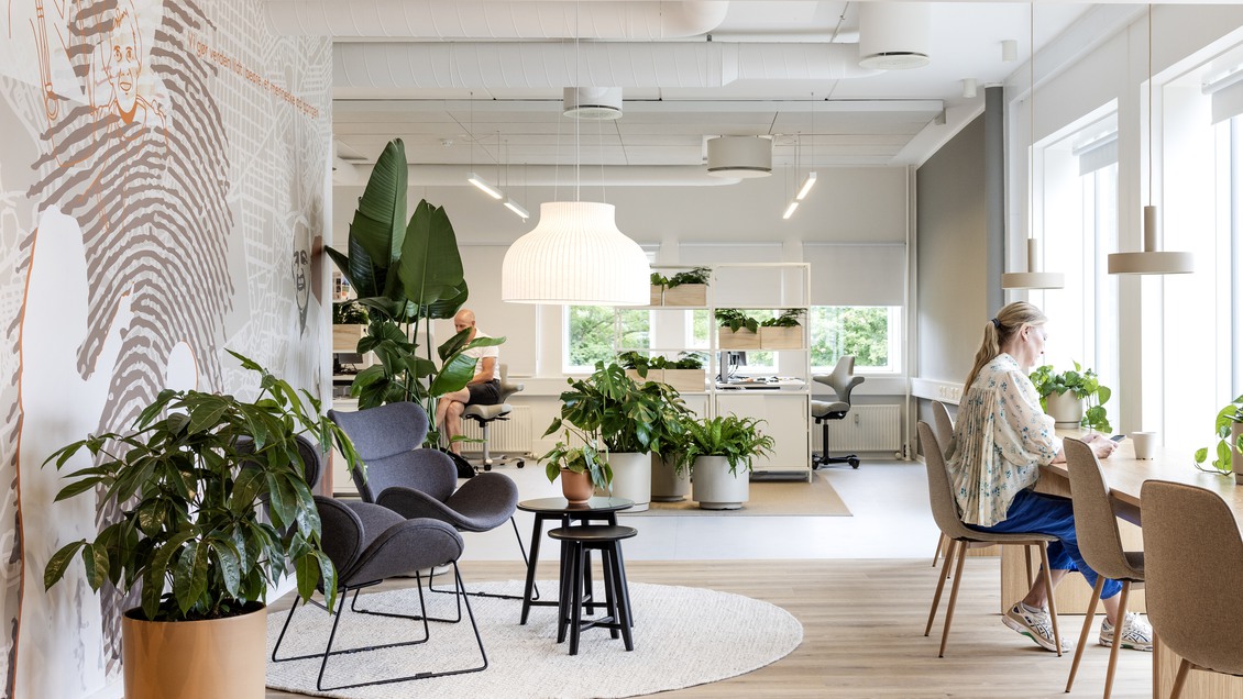 Moderne og lyst kontormiljø i Ballerup med grønne planter og indbydende loungeområder til erhvervslejemål.